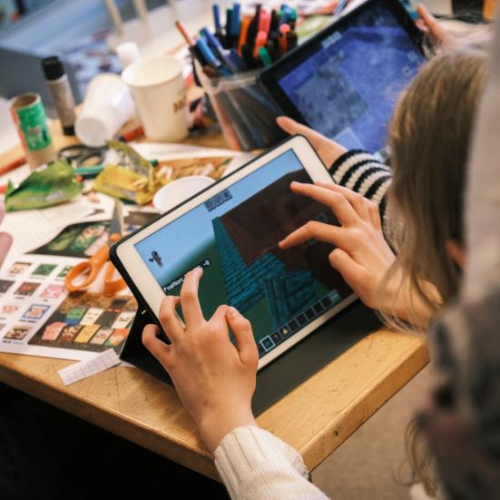 Fotografi af børn der spiller på iPad og klippe-klistrer