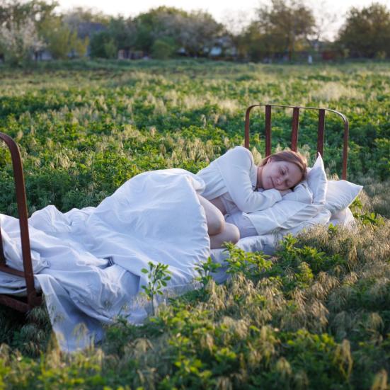 Fotografi af person der sover i seng midt i en mark