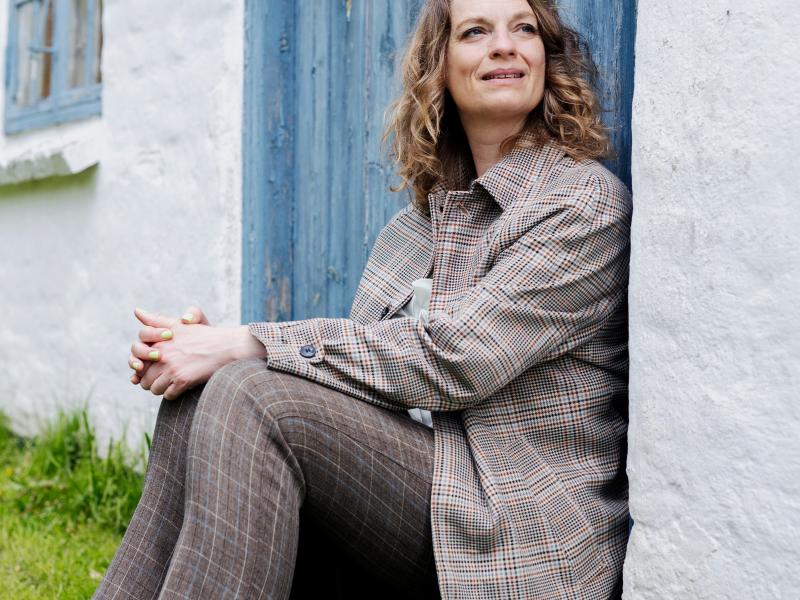Charlotte Weitze siddende ved dør til landejendom