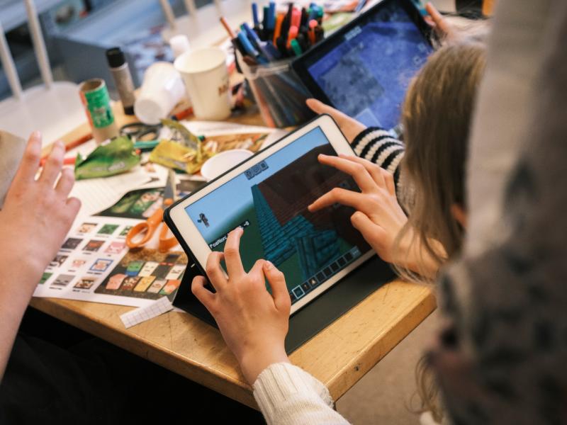 Fotografi af børn der spiller på iPad og klippe-klistrer