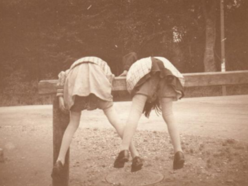 Billedet forestiller to piger, der klatre på den bom, der var  udenfor Louis Kettners forretning til at tøjre heste ved. 