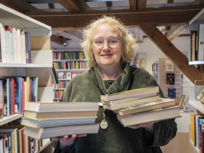 Foto af bibliotekar Dorte Hansen der står med to stakke bøger