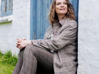 Charlotte Weitze siddende ved dør til landejendom