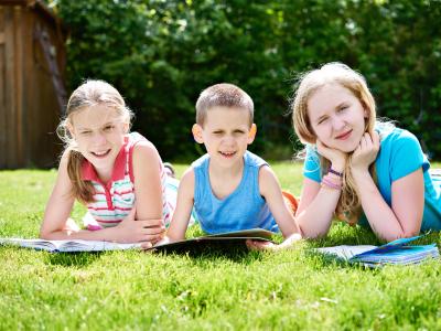 Fotografi af børn der ligger på græsplæne og læser
