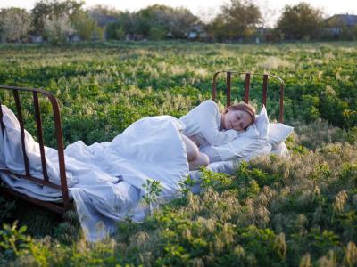 Fotografi af person der sover i seng midt i en mark