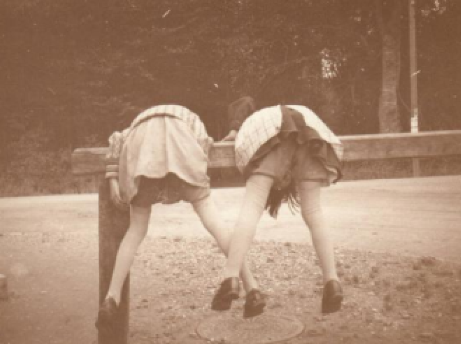 Billedet forestiller to piger, der klatre på den bom, der var  udenfor Louis Kettners forretning til at tøjre heste ved. 